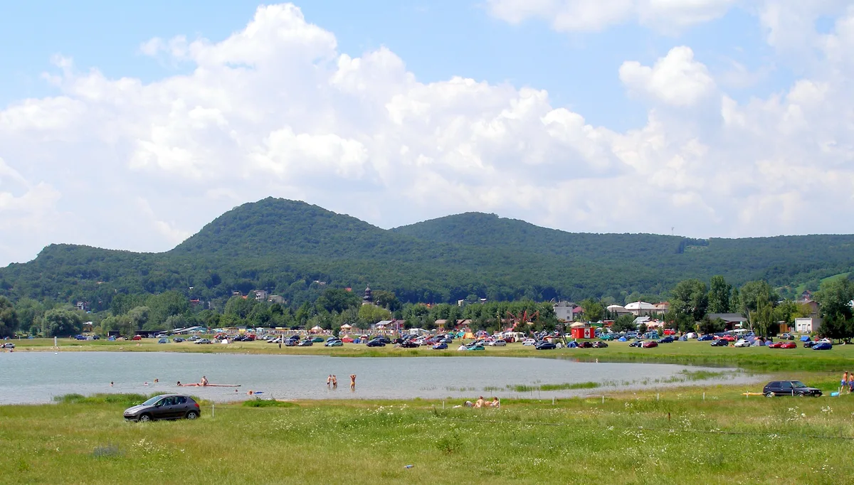 Pláž pri Kamenci s odstavenými autami a kúpajúcimi sa, v pozadí kopce Vihorlatu.